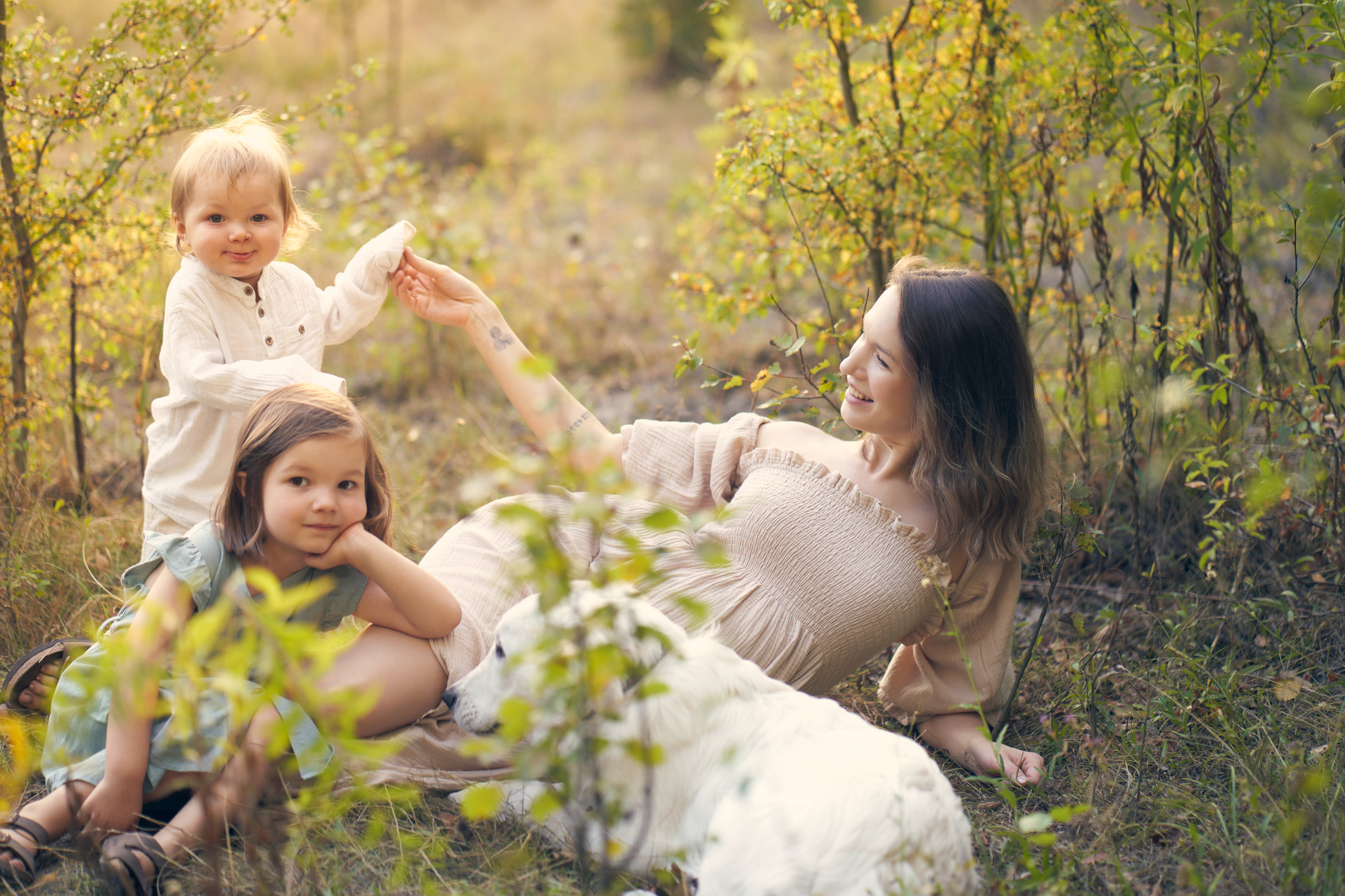 Mama i dzieci leżą w ciepłym świetle wśród roślin